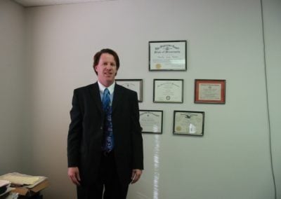 Attorney Theisen standing in front of his diplomas